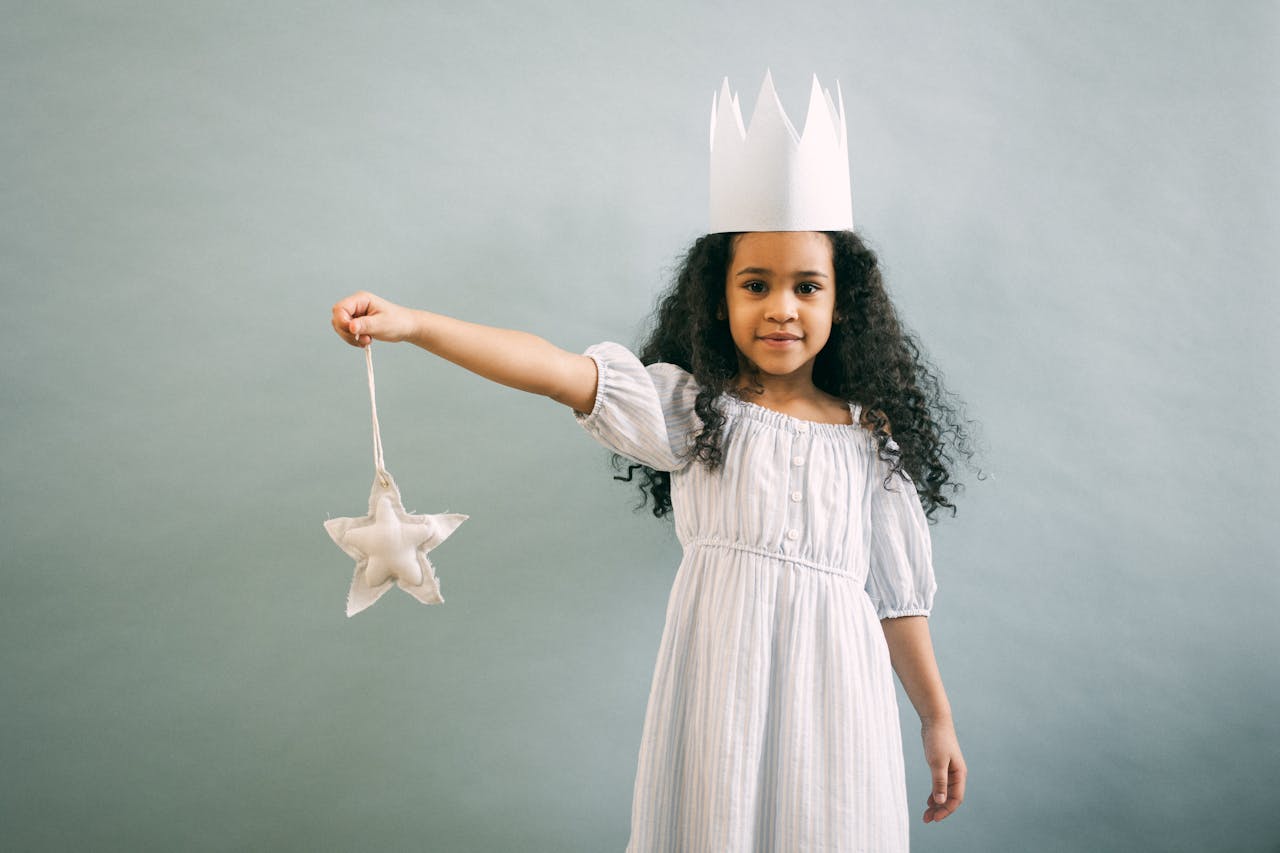 gallery-03 Adorable girl in a paper crown holding a star ornament, exuding fantasy and charm.