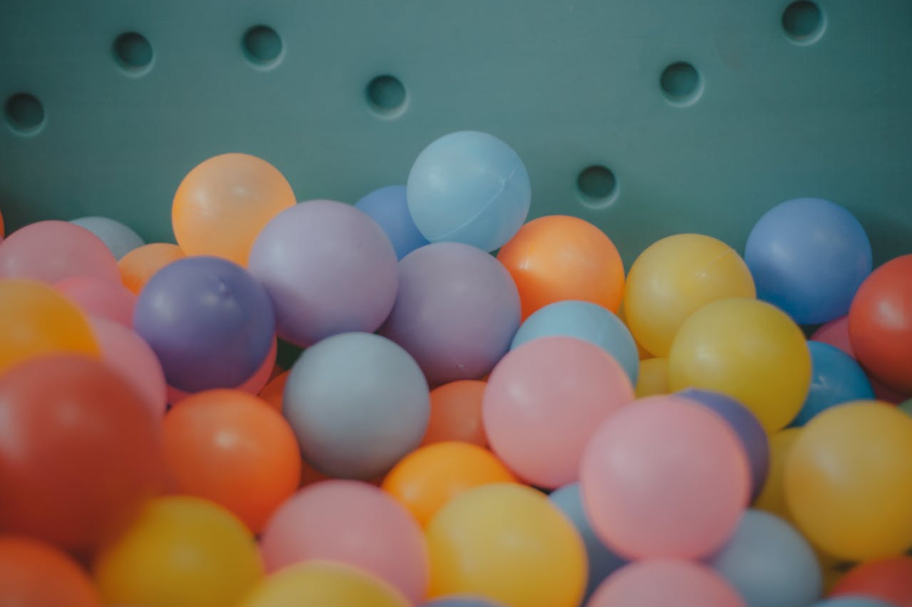 gallery-04 A close-up view of a colorful assortment of plastic balls in a ball pit, showcasing vibrant hues.