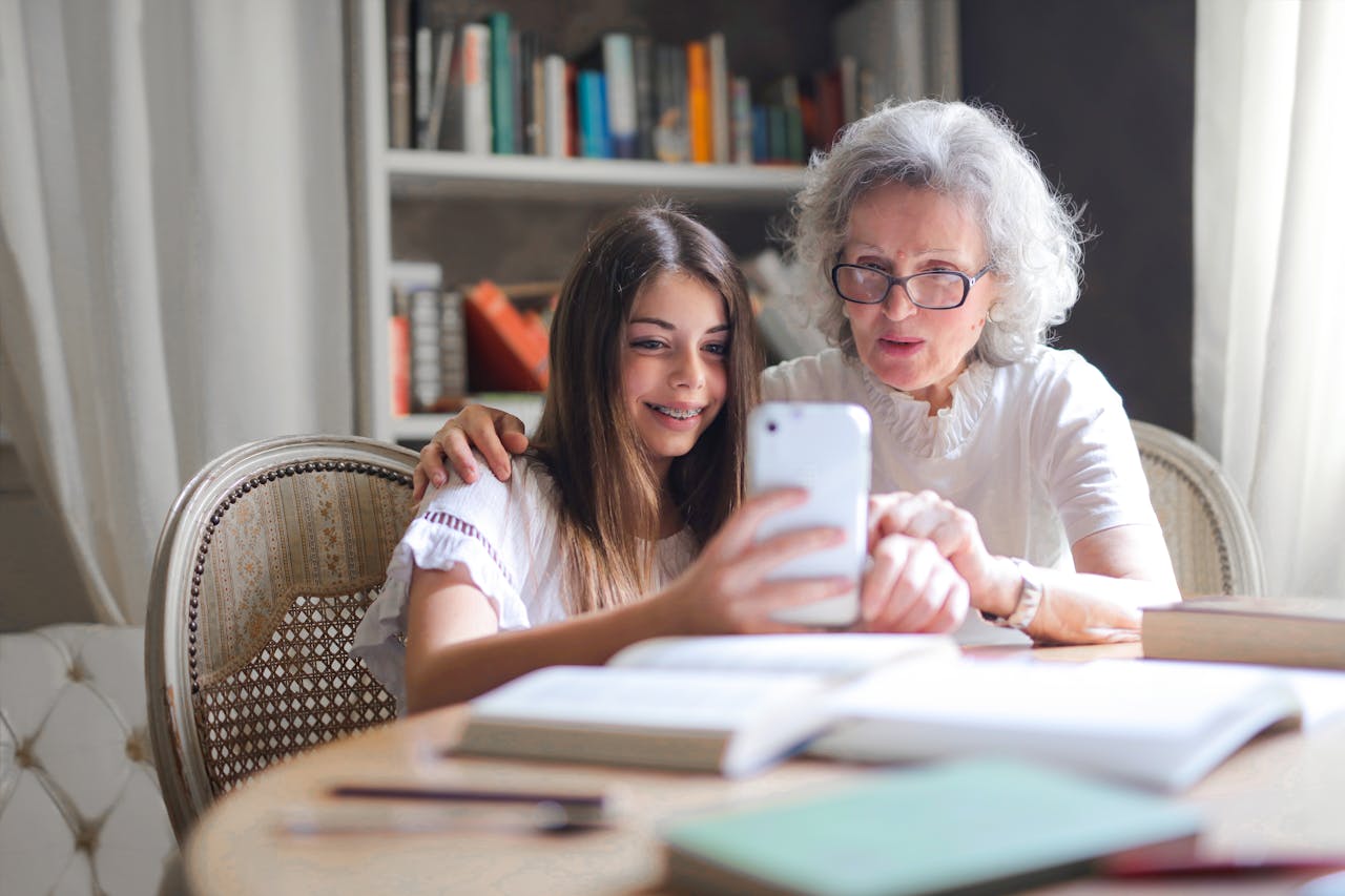 portfolio-04 A grandmother and granddaughter bonding over a smartphone at home, showcasing generational connection.
