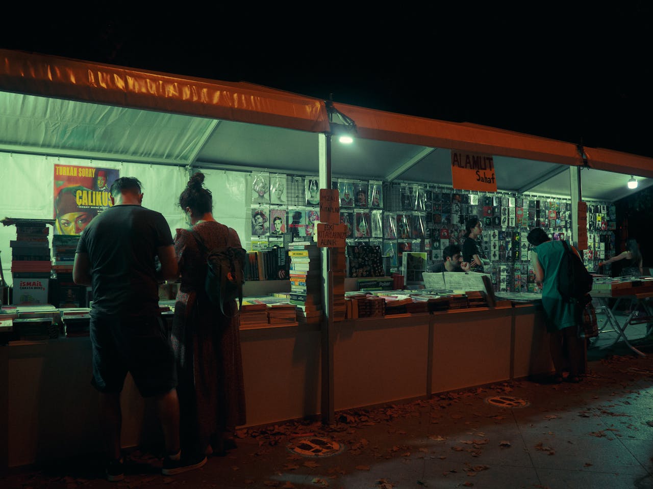 Discover a vibrant nighttime book market in İstanbul, bustling with avid readers and colorful stalls.