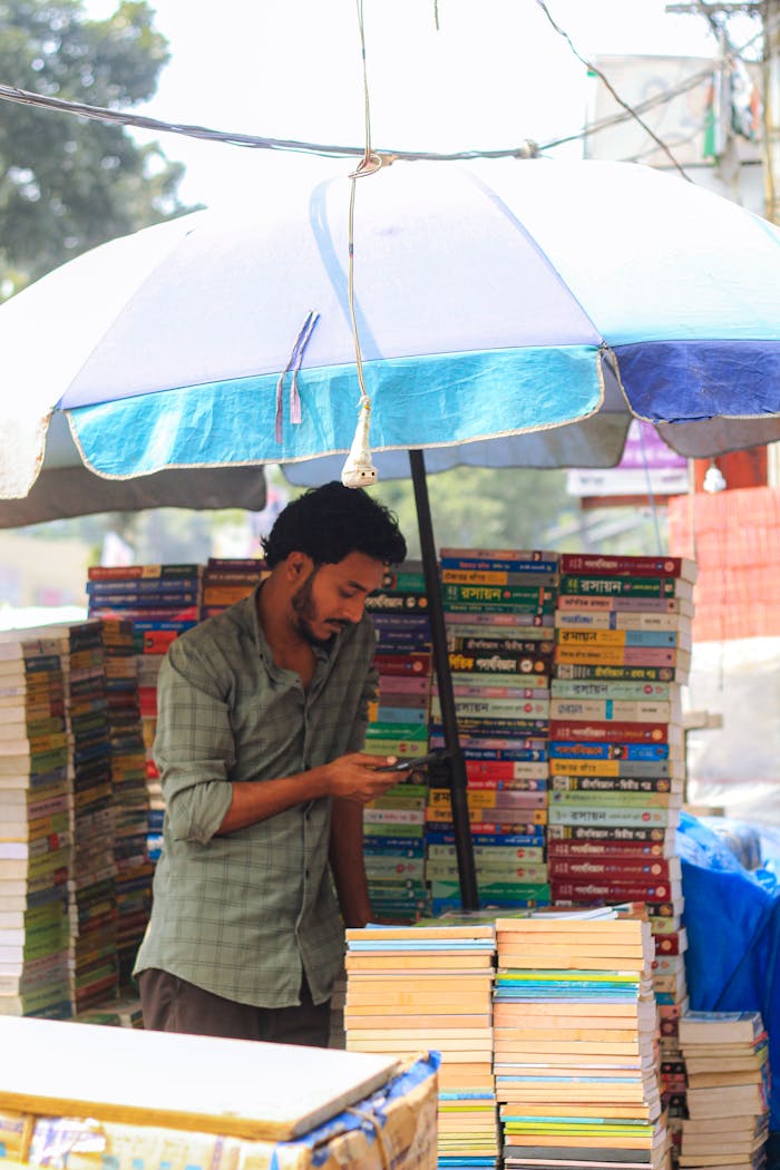 services-02 A man sells books under an umbrella in a bustling street market in Dhaka, Bangladesh.