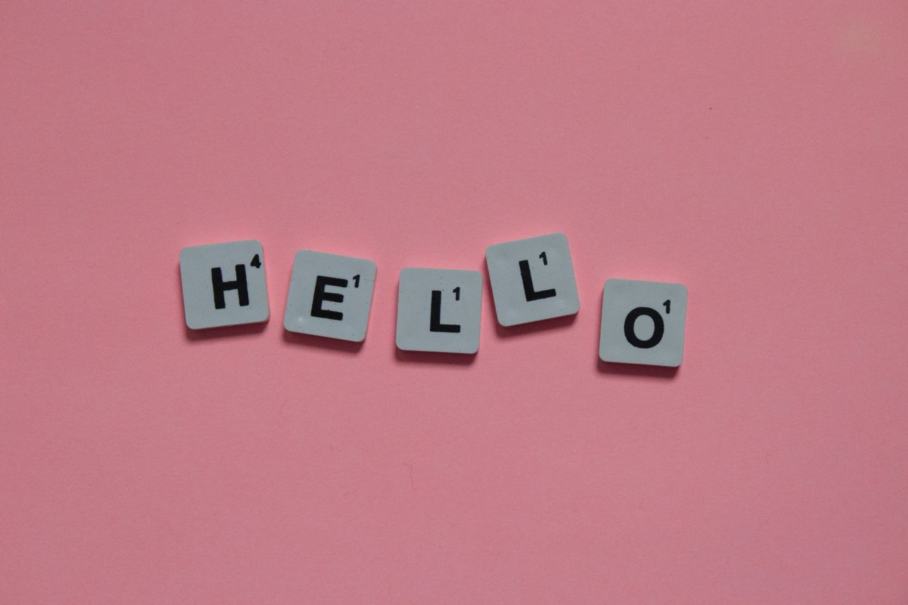 team-02 Scrabble tiles arranged to spell hello on a soft pink background, with copy space.