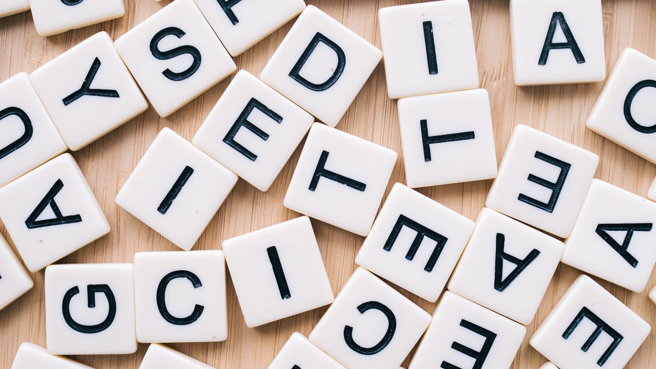 team-04 Closeup of scattered scrabble tiles against a wooden background, ideal for word games and learning themes.