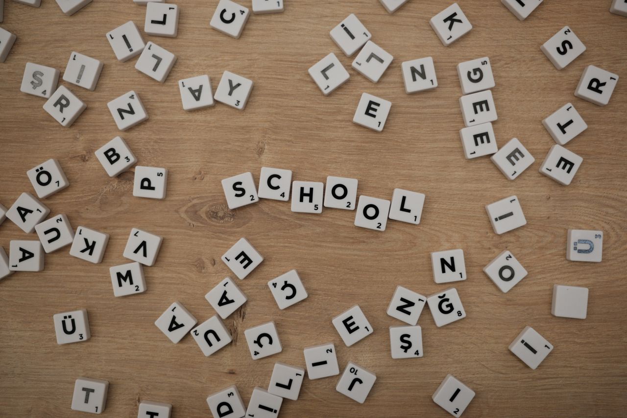 Scattered Scrabble tiles on wood with School spelled out, ideal for educational themes.