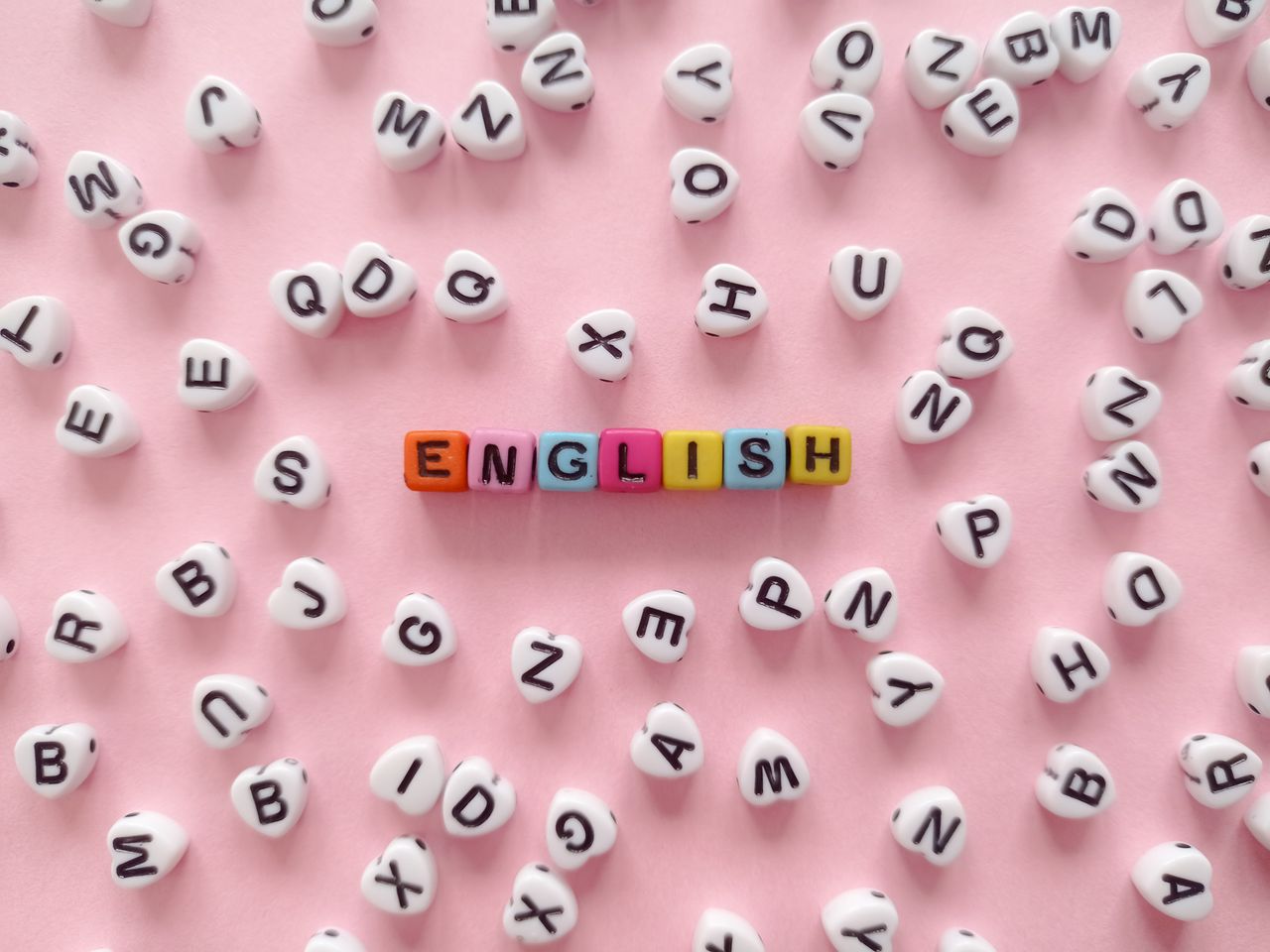 team-01 Scattered letter beads form the word English on a pink background, symbolizing language learning.